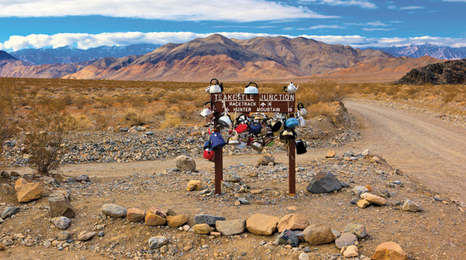 Teapots and kettles on top of and hanging from the roadside sign