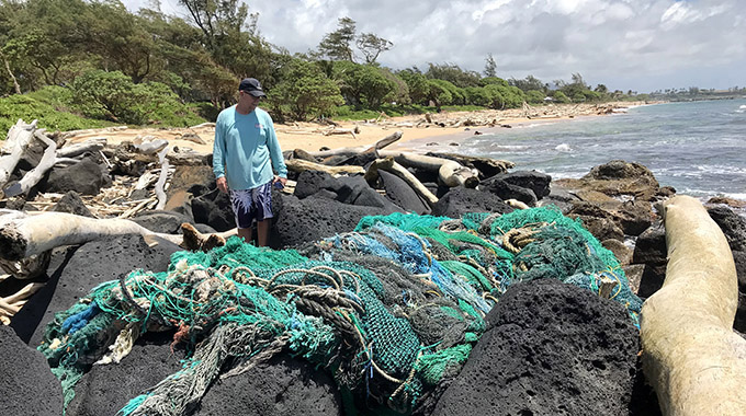 Surfrider Foundation Kauai Chapter volunteer Keith Rich assesses a large ghost net at Lydgate Beach.