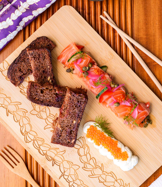 Charcuterie board topped with bread, cream cheese, and salmon slices.