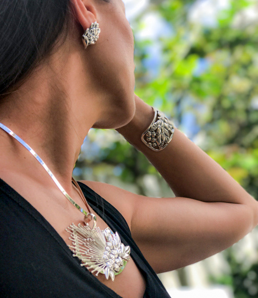 Woman wearing earrings, bracelet, and necklace from Paradisus Jewelry's Ohi'a Lehua collection