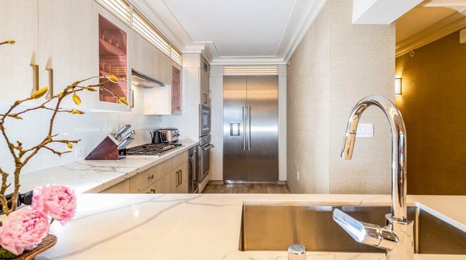 Rose-tinted doors accent white cabinets in an Espacio guest room kitchen