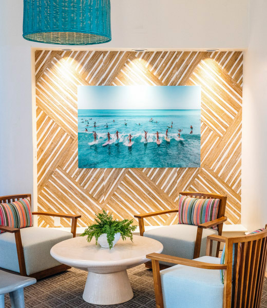 Lights highlight artwork of surfers in a Kaimana Beach Hotel seating area