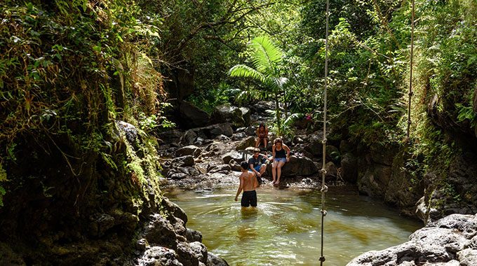 A man walking in a small pool of water as 3 people watch from shore