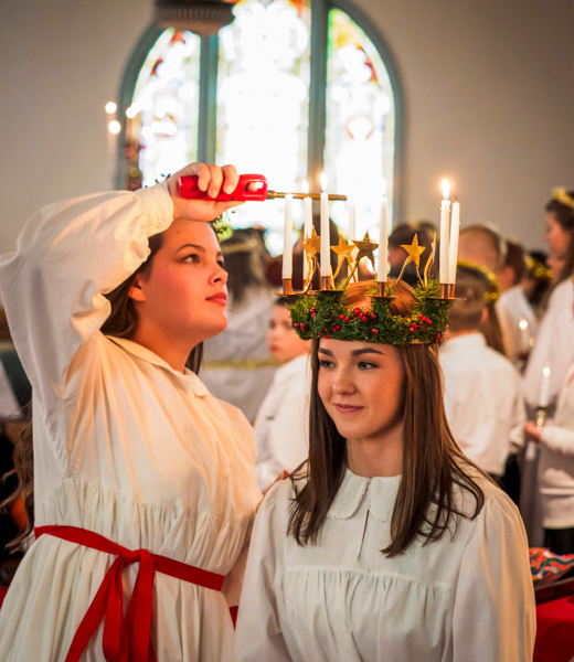 Student lighting the candles on the wreath headpiece for the girl portraying St. Lucia.