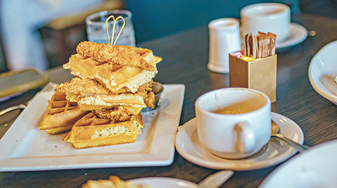 Chicken and waffles served beside a cup of coffee