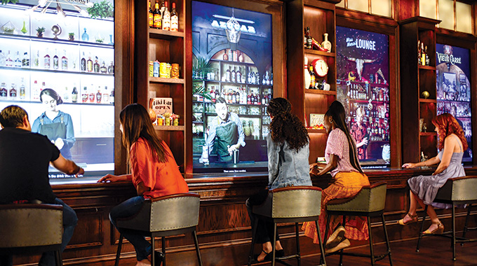 Guests seated before virtual bartenders at Sazerac House