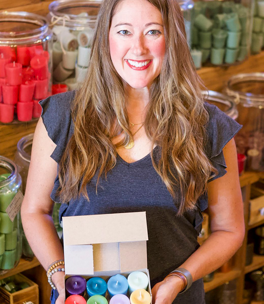 Lori Block holding a box of candles insider her shop.