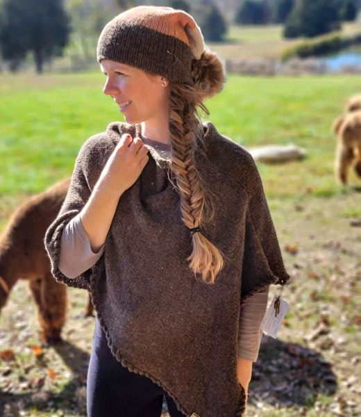 Woman wearing a poncho and hat knit from alpaca yarn.