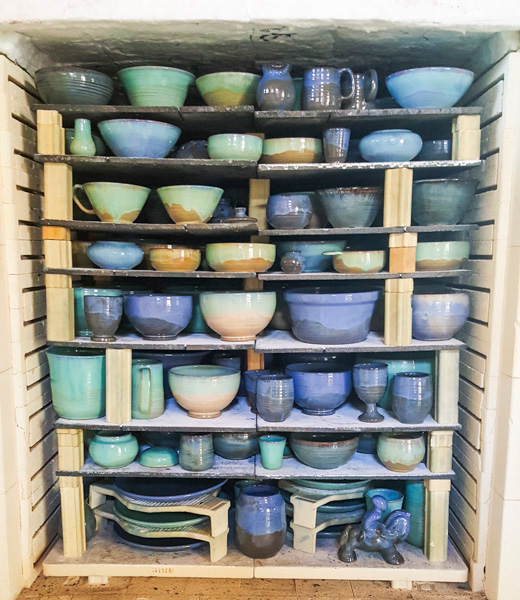 Kiln filled with ceramics including bowls and cups.