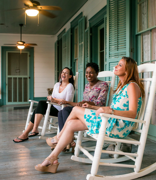 Trio of women relaxing in porch rocking chairs.