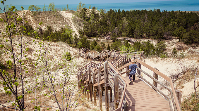 A young boy descending the boardwalk staircase toward the dunes