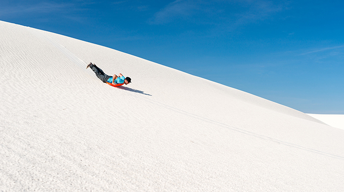 Someone sledding down the dunes at White Sands National Park