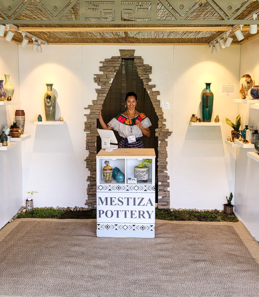 Mucuy Bolles behind a Mestiza Pottery sign.