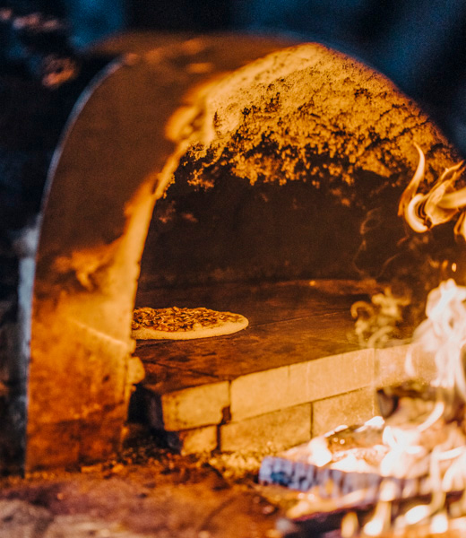 Pizza cooking inside a stone pizza oven at American Flatbread