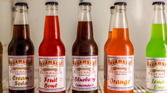 Glass soda bottles containing Cream Soda, Fruit Bowl, Blueberry Lemonade, Orange, and Lemon Lime flavors