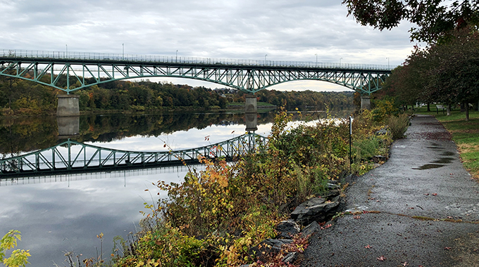 At the start of the Kennebec River Rail Trail in Augusta, Maine, cyclists ride under Memorial Bridge. | Photo by Earl Kingsbury