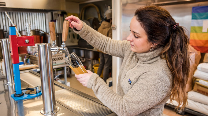 Brunnette woman pouring a draft beer into a tall glass