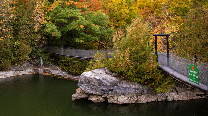 Enjoy autumn’s colors from the suspension bridge over the waterfall on Otter Creek. | Photo by Pamela Hunt