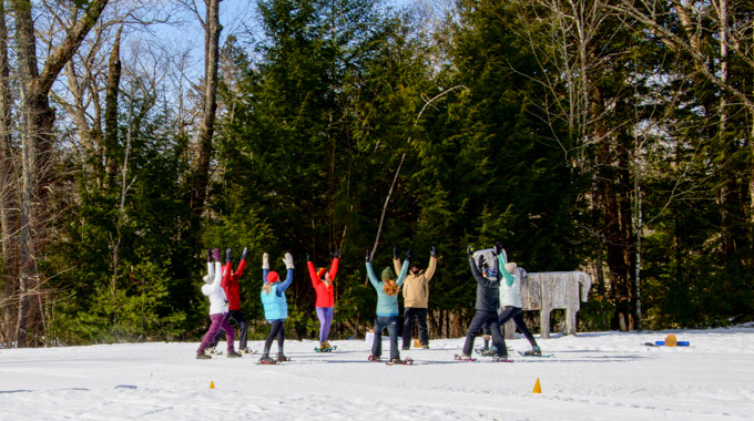 Group of snowshoers lifting their arms to the sky.