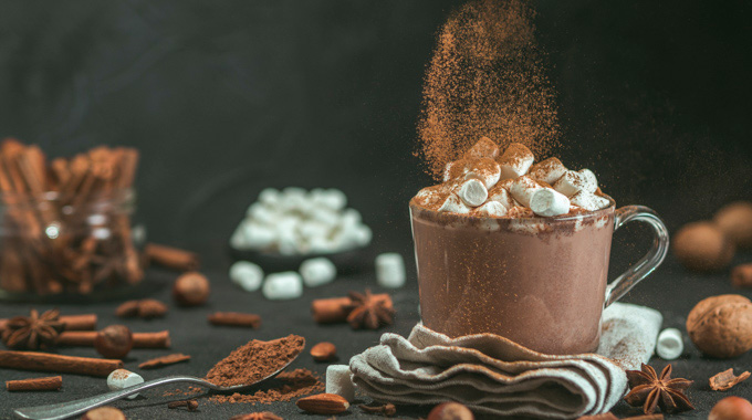 Cinnamon being sprinkled onto a glass of hot chocolate
