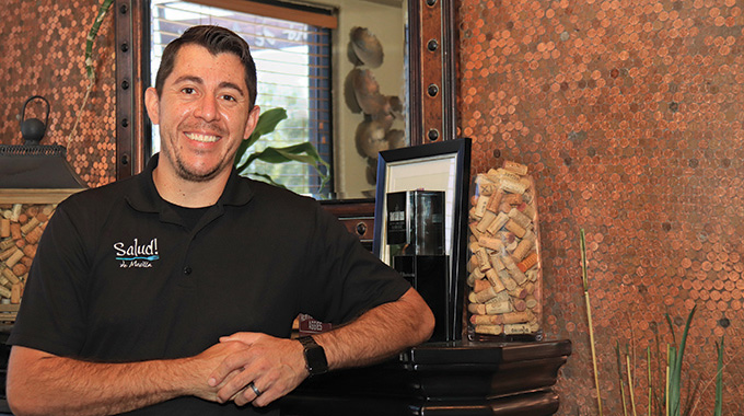 Salud! de Mesilla owner Russell Hernandez in front of his restaurant’s penny wall.