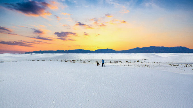 A long person standing amid gypsum at White Sands National Park.