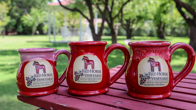 A trio of red mugs with the Red Horse Bed & Breakfast logo