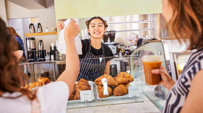 Employee handing a pastry bag to a customer at Pistacia Vera