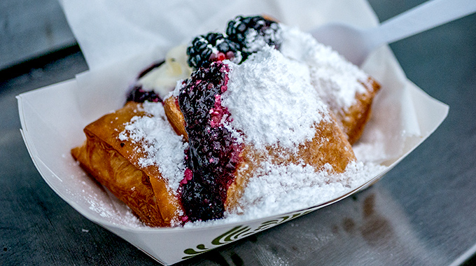 Beignets topped with blackberries and powdered sugar