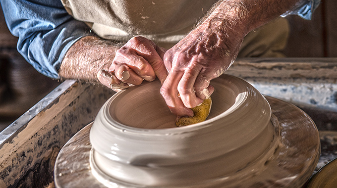 Someone shaping wet clay on a pottery wheel