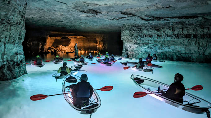 Glowing kayaks illuminate the surrounding water and cave walls