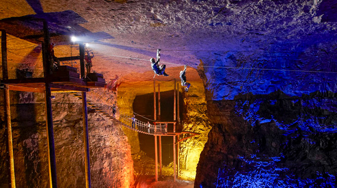 Two people zip-lining in a cavern