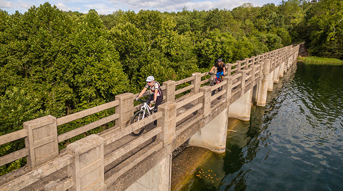 Bicyclists riding over a bridge in Lake Leatherwood City Park.