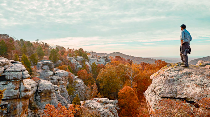 Hiker standing on a rock overlooking the Shawnee National Forest in autumn.