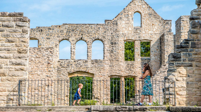 Woman watching a young child running around stone castle ruins 