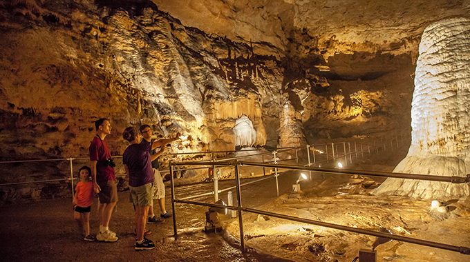 A group of 3 adults and a child touring inside a cave 