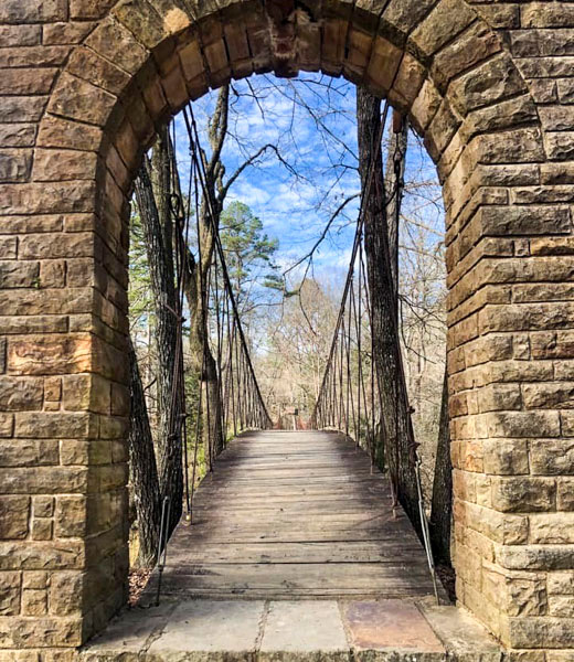 A stone archway framing a wooden footbridge