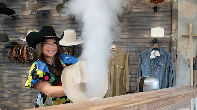 A saleswoman steams a hat at the Proper Supply Company.