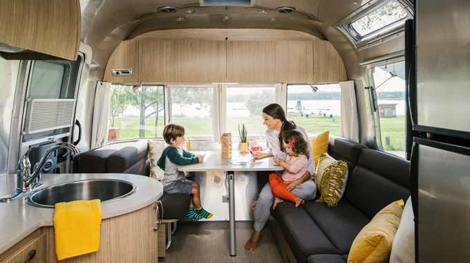 Woman and 2 children sitting at a dining table inside an Airstream trailer