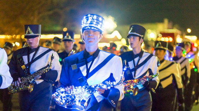 A musician holding his saxophone wrapped in lights during Boerne's Weihnachts Parade