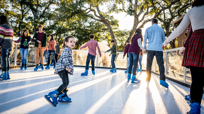 A young girl gliding amid other skaters at New Braunfels Ice Rink