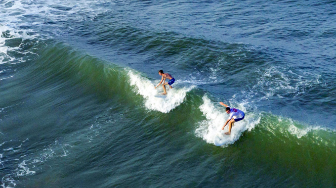 A pair of surfers catching a wave
