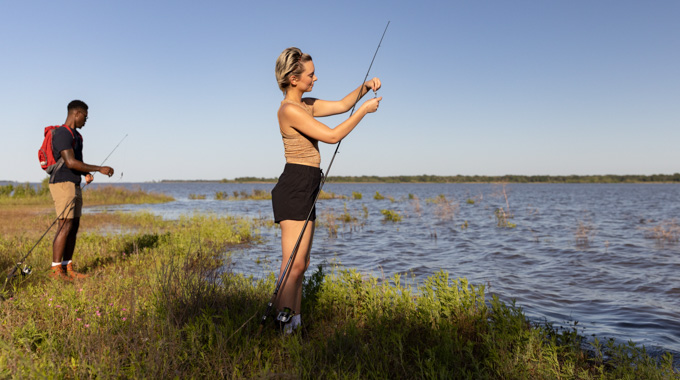 Woman preparing a fishing pole at the lakeside