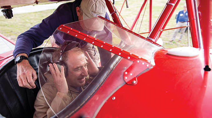 A museum worker straps writer Larry Bleiberg into the plane’s front seat.