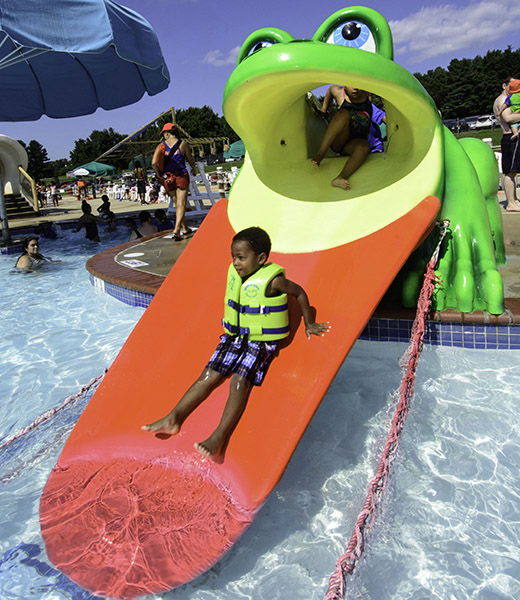A young guest enjoys the slide at the Water Mine Family Swimmin’ Hole at Lake Fairfax Park Campground. | Photo by Don Sweeney/Fairfax County Park Authority