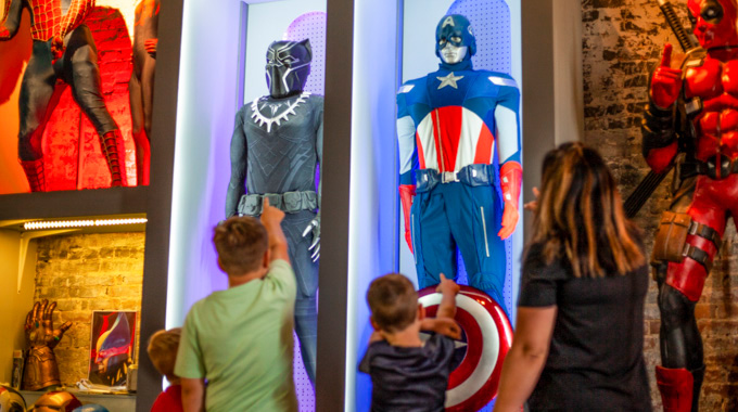 A group of children pointing toward Captain America and Black Panther displays
