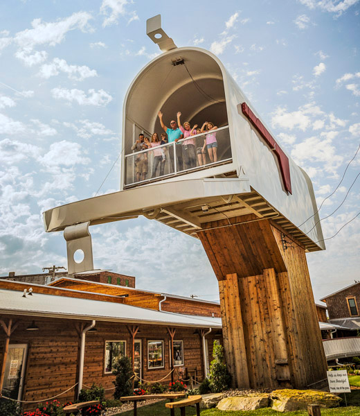People waving from inside a giant mailbox-shaped structure