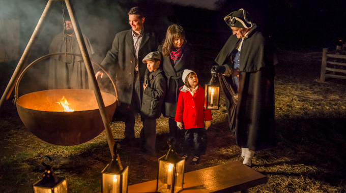 Reenactors standing beside a family during a candlelight tour of Mount Vernon