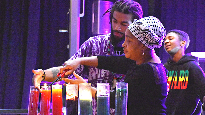 People lighting candles during the Capital City Kwanzaa Festival