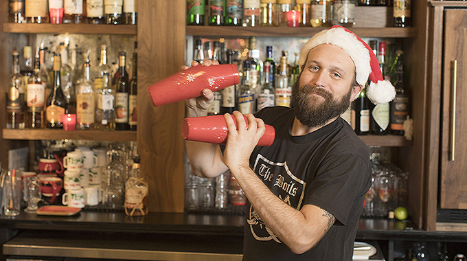 A bartender with a Santa hat shaking up drinks